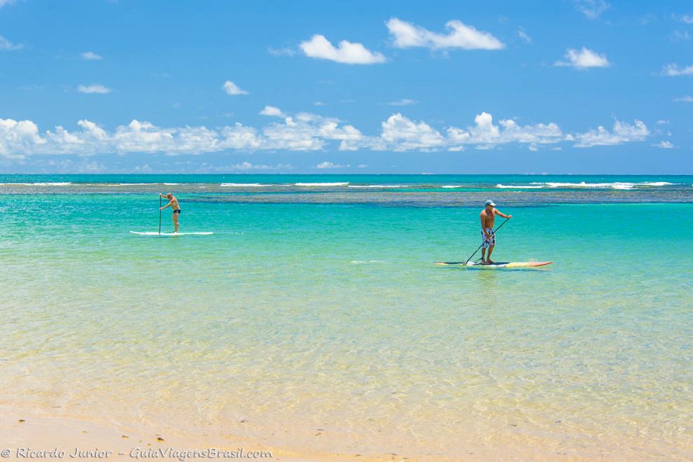 Imagem de duas pessoas praticando stand up paddle neste mar magnífico.